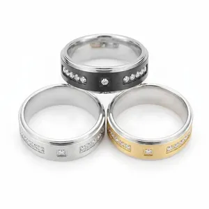 Détail de trois bagues en acier inoxydable en noir, or et argent avec incrustations de zircons.