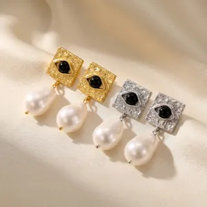 Close-up view of textured square evil eye earrings with elegant white Baroque pearls