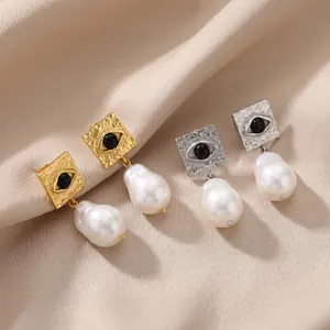Close-up view of elegant stainless steel gold and silver Evil Eye earrings with baroque pearls