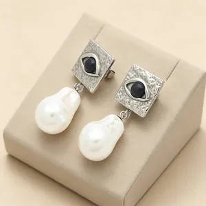 Close-up of evil eye geometric earrings with textured silver finish and pearls
