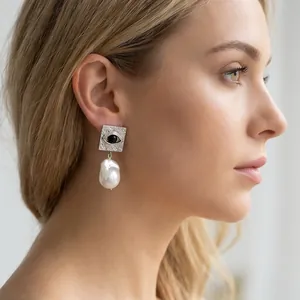 Detail view of Evil Eye square silver earring with a large baroque pearl on model