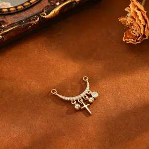 Detailed view of a gold moon pendant with pavé zircons and hanging cross charm.