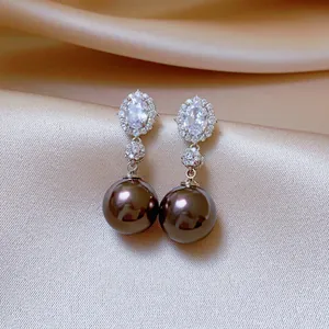 Detailed shot of elegant silver needle drop earrings with oval zirconia and dark pearls