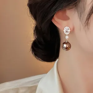 Macro detail of elegant zircon cluster and metallic pearl drop earrings on model