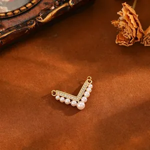 Detail shot of elegant V-shaped copper pendant with pearls and cubic zirconia stones