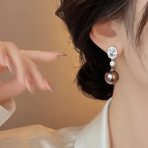 Elegant oval zircon drop earrings with a metallic brown pearl on a graceful model's ear