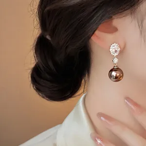 Macro detail of luxury coffee pearl drop earring with oval zircon studs on model