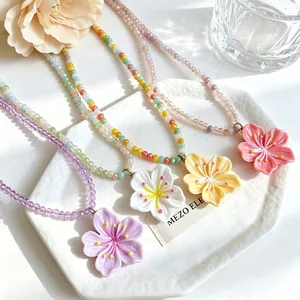 Close-up view of vibrant beaded necklaces featuring pastel flower pendants on a white plate