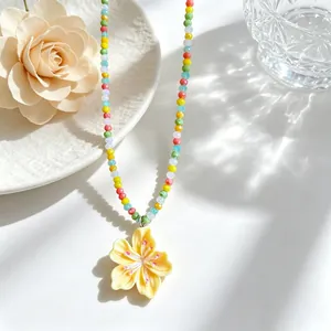Detail of colorful beaded necklace with a vibrant yellow flower pendant for summer.