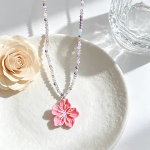 Close-up of a sweet pink cherry blossom pendant with colorful pastel beaded chain necklace