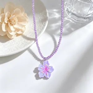 Close-up detail of a purple beaded necklace with a sweet cherry blossom pendant