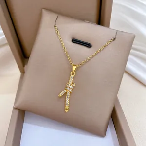 Macrodetail van goudkleurige ketting met knoopvormige hanger en kristallen op kussentje.