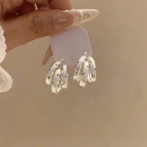 Detailed view of French style triple-layered C-shape earrings with black polka dots
