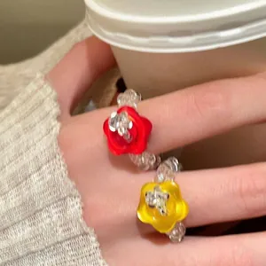Close-up of vibrant glass beaded rings featuring red and yellow resin flowers.