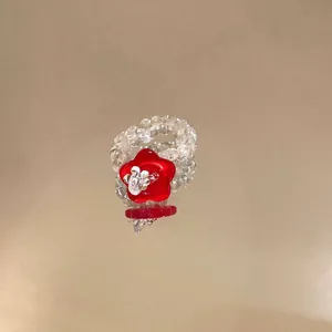 Close-up of glass beaded ring featuring a vibrant red resin flower center