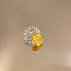 Detailed close-up of a handmade glass beaded ring with a vibrant yellow resin flower ornament