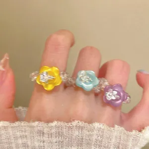 Close-up detail of colorful dopamine-style resin flower beaded rings worn on fingers