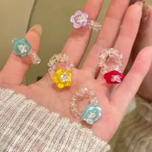 Close-up of colorful resin flower rings with faceted glass beads on a model's hand.