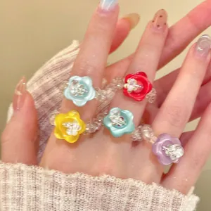 Close-up detail of colorful resin flower rings with glass beads on model's hand