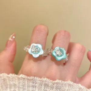Detail view of a beaded glass ring with a blue resin flower and crystal center.