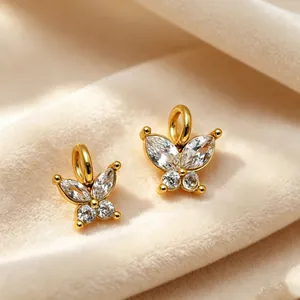 Gros plan de pendentifs papillon dorés avec des ailes en cristal de zircon étincelant.