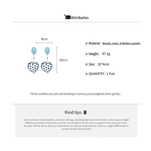 Detail view of heart-shaped resin earrings with beads and size measurements