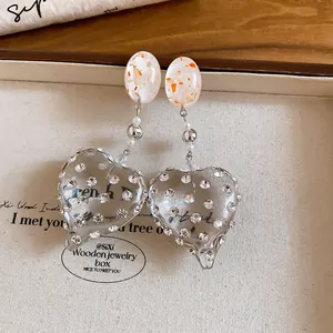 Close-up of sweet resin heart earrings with sparkling rhinestone studs and gold flakes.