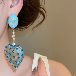 Close-up of blue resin heart earrings with sparkling rhinestones in dopamine style