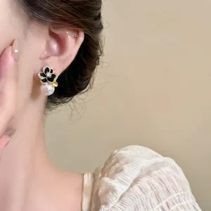 Boucles d'oreilles camélia noir élégantes avec zircon et perle, vue détaillée.