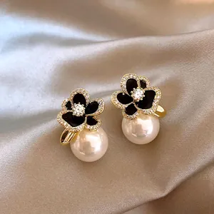 Détail de boucles d'oreilles fleurs noires serties de zircons et perles blanches