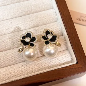 Détail en gros plan d'élégantes boucles d'oreilles camélia noir avec zircon et perle