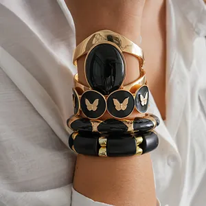 Gros plan de bracelets épais en acrylique noir et or rétro avec motif papillon