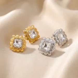Close-up of geometric square stud earrings with textured gold and silver frames
