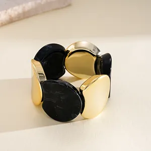 Détail en gros plan d'un bracelet géométrique épais en acrylique noir et doré rétro
