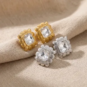 Detailed view of textured gold and silver square stud earrings with crystals