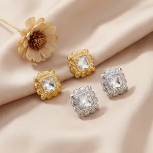 Detail view of geometric square stud earrings with textured frames in gold and silver finish