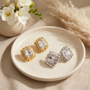 Close-up detail of square crystal stud earrings with elegant linear pleated metal texture