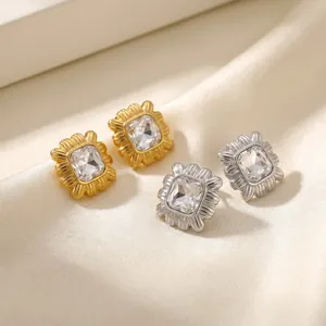 Detailed macro view of 18k gold and silver plated square textured stud earrings with crystals.