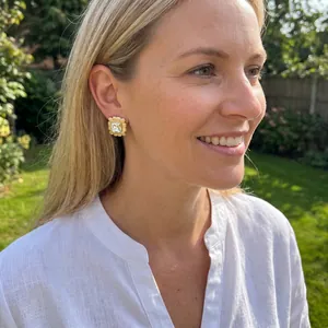Detailed side view of a gold-plated square stud earring worn on a female model