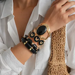 Gros plan sur un ensemble de bracelets vintage en acrylique noir et doré au poignet