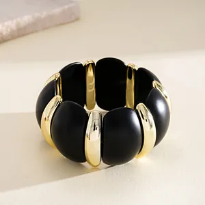 Gros plan d'un bracelet en acrylique noir et doré avec une finition mate élégante.