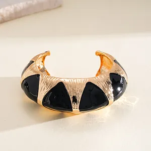 Gros plan sur un bracelet manchette doré avec incrustations géométriques noires