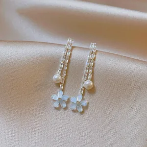 Detail shot of long tassel earrings with sparkling zircons, white pearls, and blue flowers.