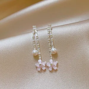 Detail shot of elegant tassel earrings with zircons, a pearl, and pink flower charm