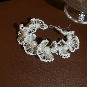 Vue détaillée d'un bracelet en dentelle de perles blanches et cristal sur une surface en cuir