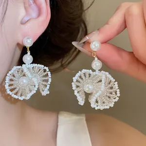 Détail de boucles d'oreilles pendantes élégantes en dentelle de perles et cristaux.