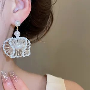 Gros plan de boucles d'oreilles fleurs en perles et cristaux faites à la main de style français.