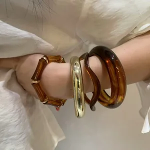 Stijlvolle set van amberen acryl armbanden en goudkleurige armband