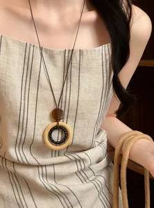 Detailansicht einer ethnischen Kette aus Harz und Holzperlen auf einem gestreiften Kleid
