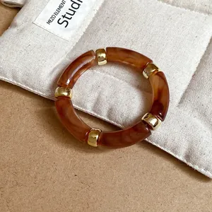 Macro-detail van een amberkleurige acryl armband met elegante gouden tussenstukken